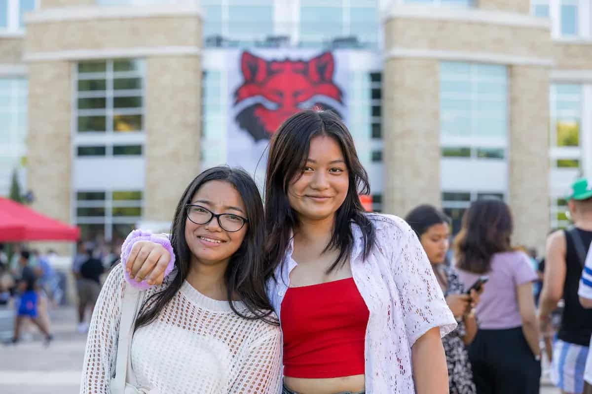 Students smiling in front of a Red Wolves banner at a campus event