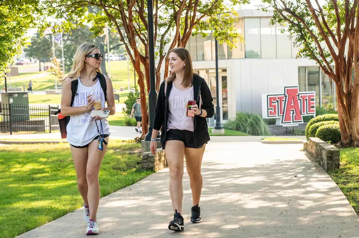 Students walking past the Arkansas State sign