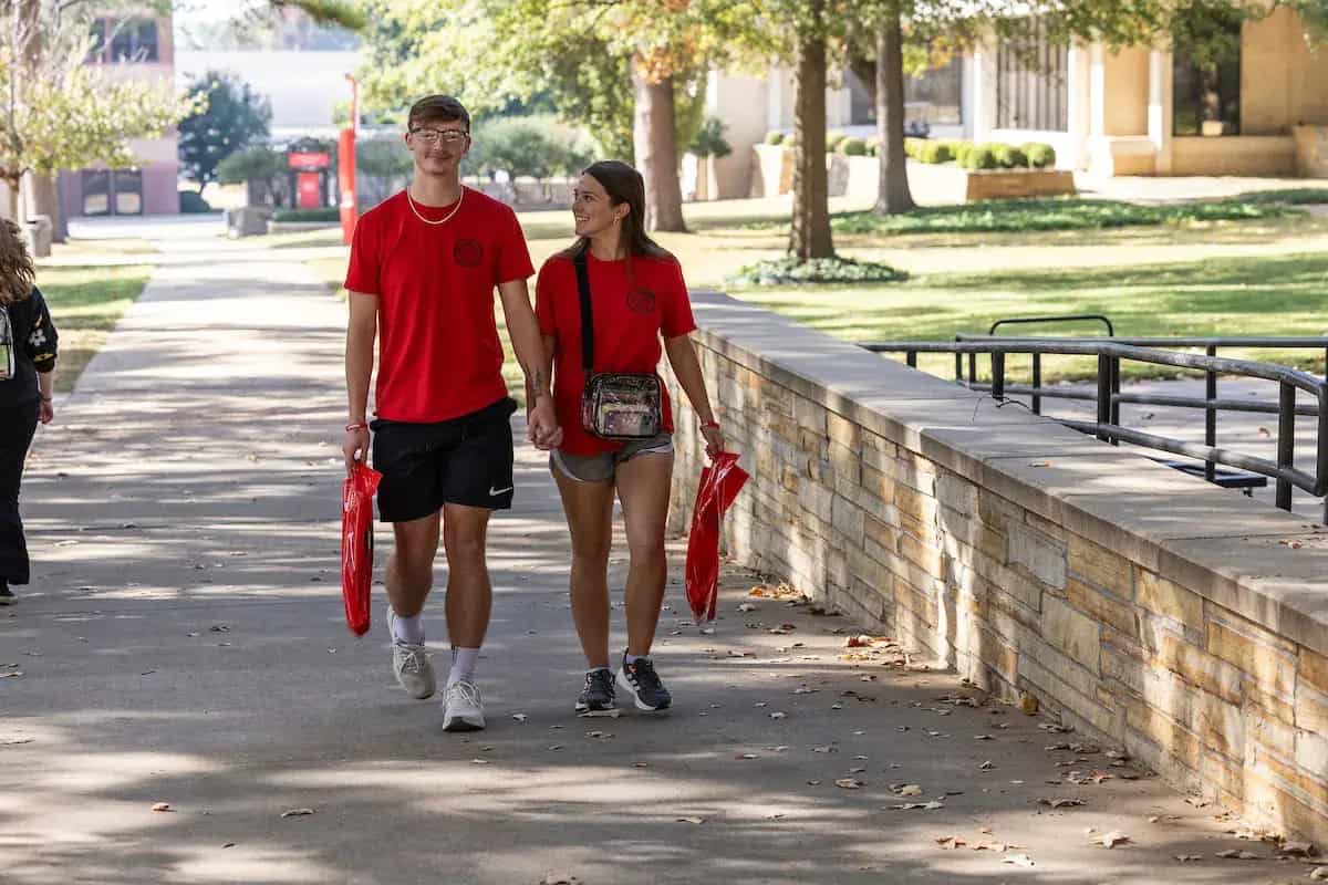 Two students walking on campus in red A-State shirts